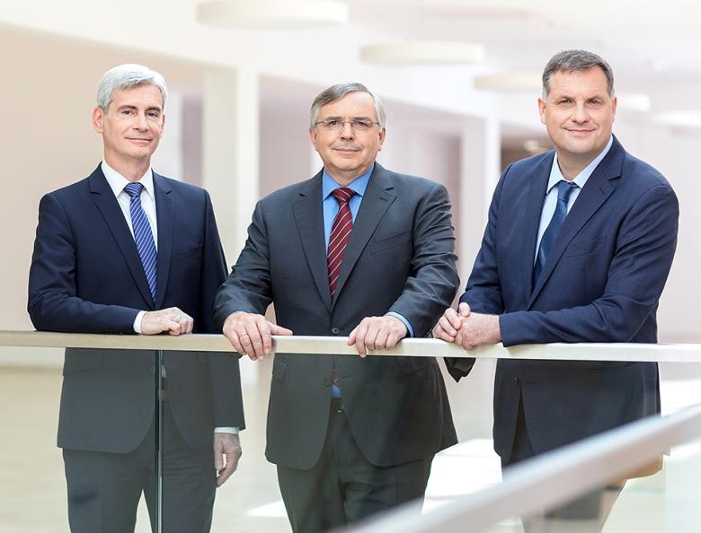 Drei Wiener Netze Geschäftsführer im Anzug lehnen an einem Stiegengeländer